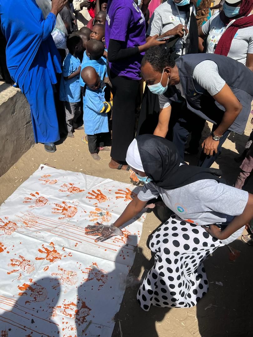 Community members leave handprints on a cloth during a GBV awareness activity