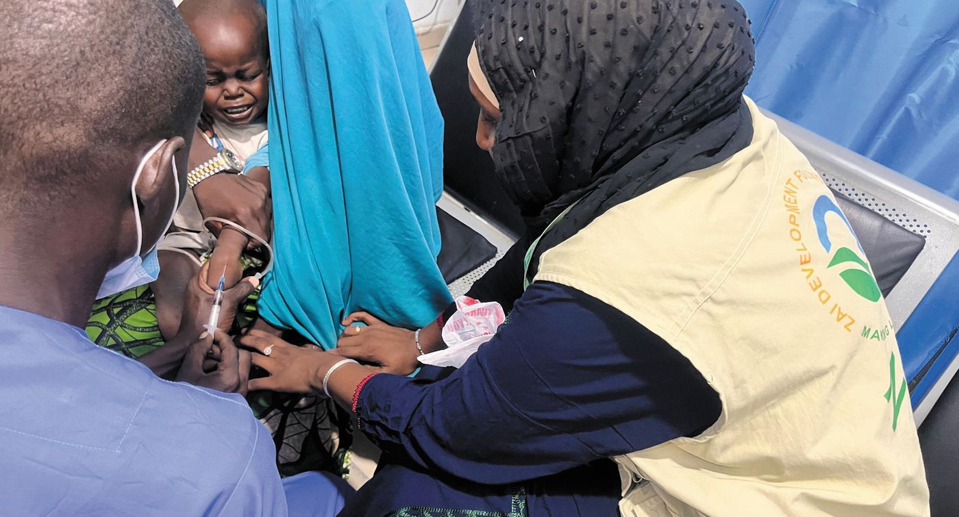 A ZAIDF team member helps a mother and child at a hospital during flood response