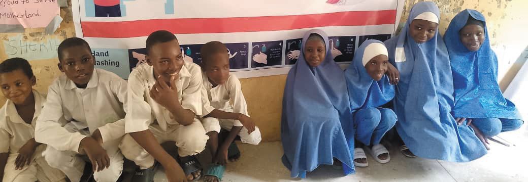 Boys and girls seated in front of a hygiene poster at a children's hygiene club