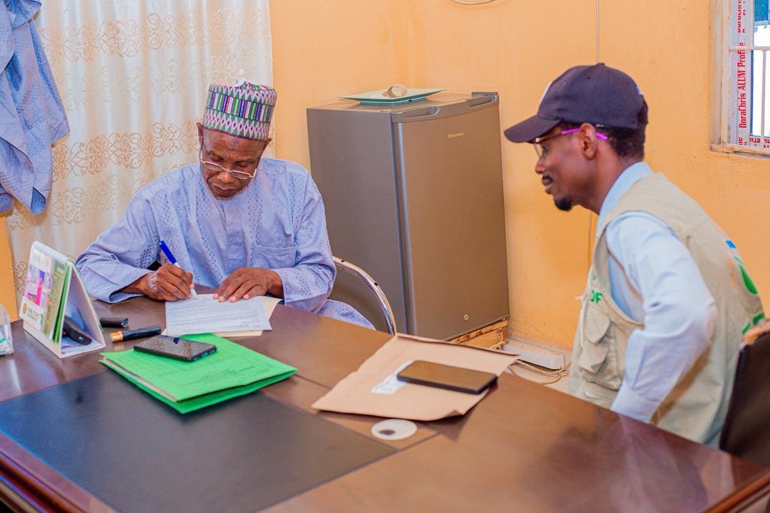 A ZAIDF team member and a community member at a desk during a field visit