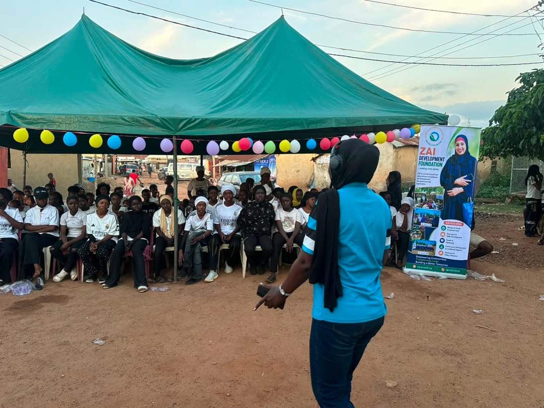 A facilitator addresses participants seated in rows under the canopies