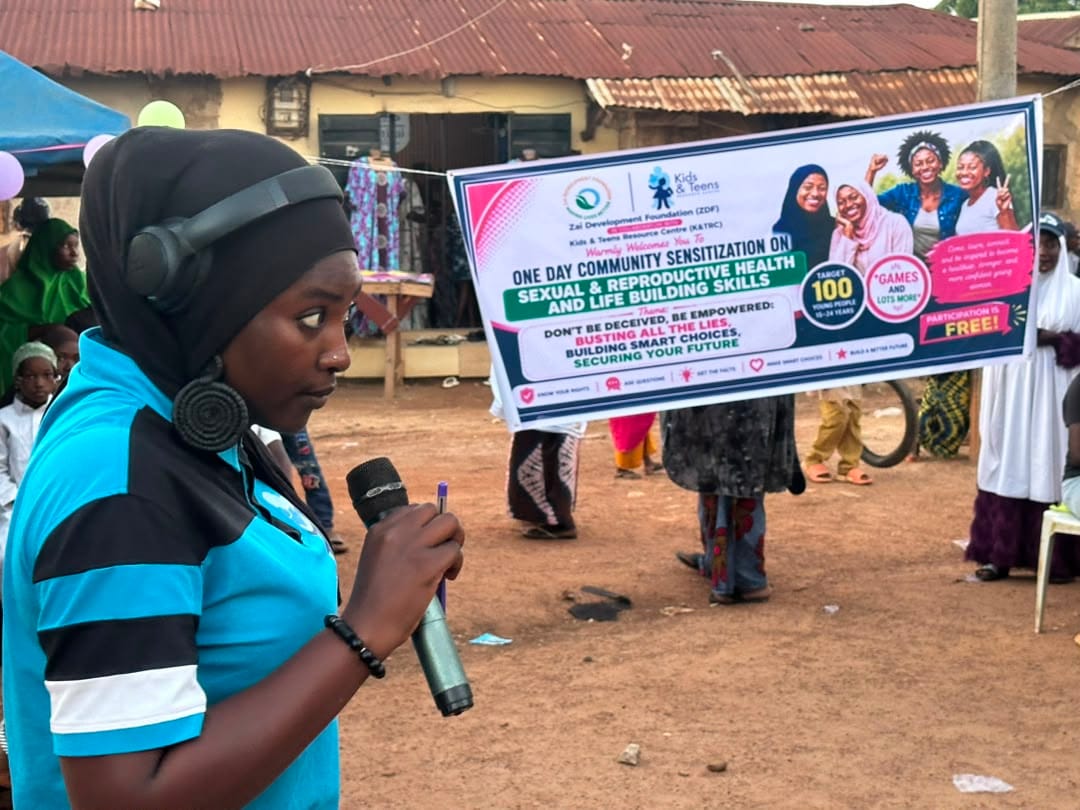 A facilitator speaks into a headset microphone in front of the session banner