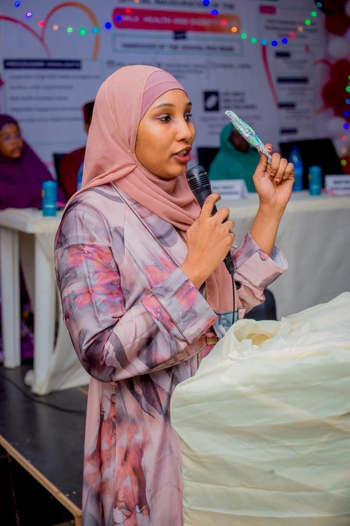 A speaker addresses the audience from a microphone at the session table