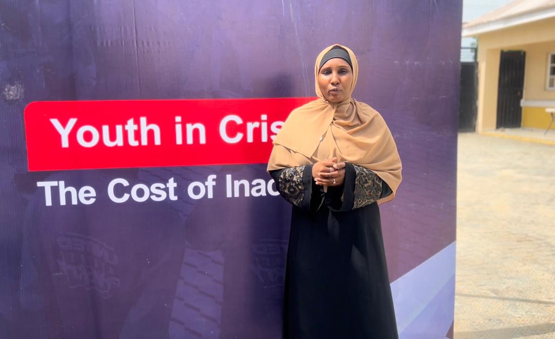 A ZAIDF representative speaks in front of a "Youth in Crisis" banner during a youth engagement session in Borno State